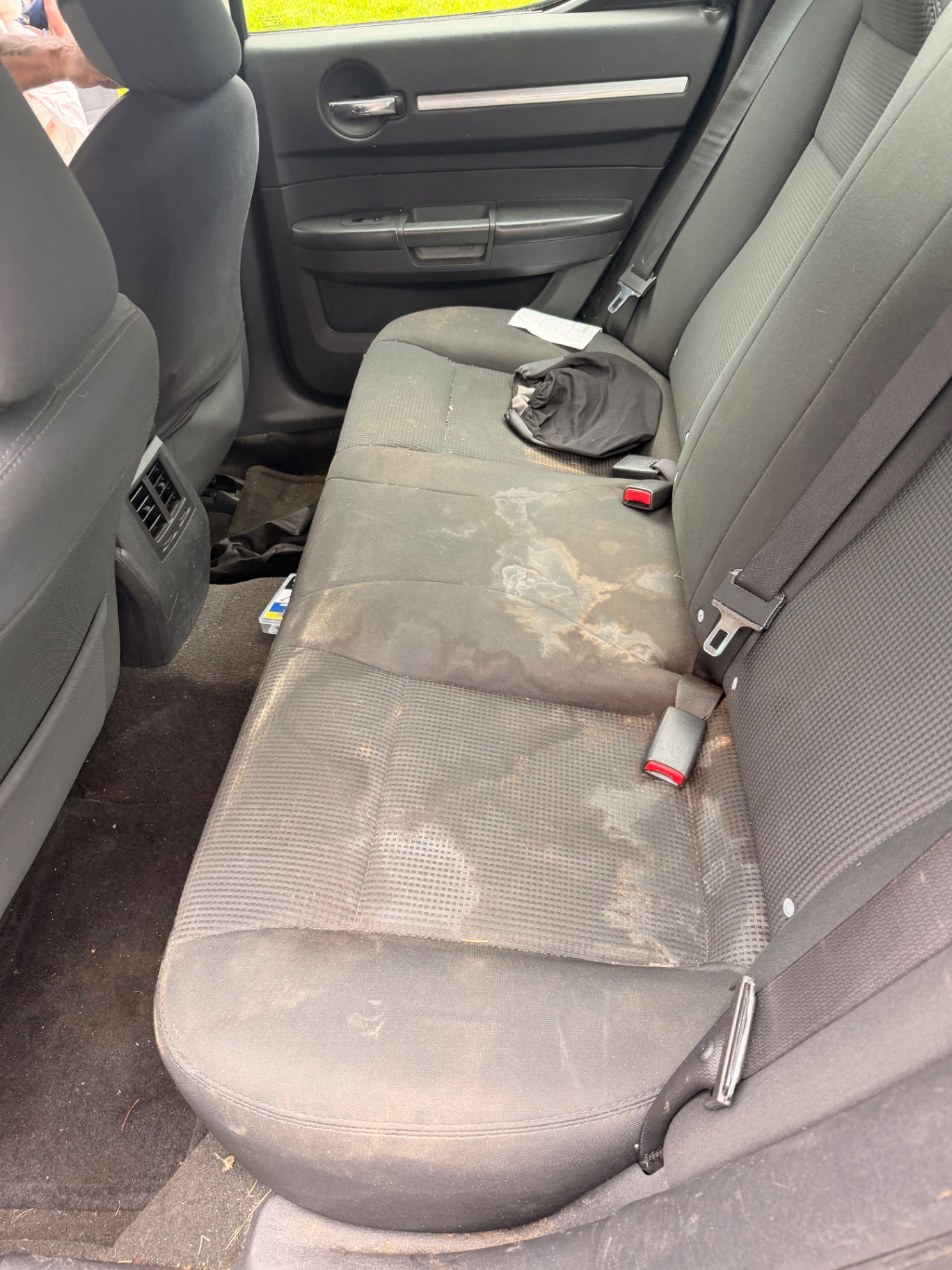 Rear car seat heavily stained and soiled before a mobile interior detail